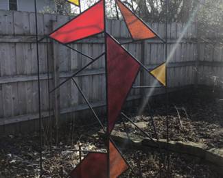 Great piece of garden art. made of rebar and plexiglass with yellow orange and red shapes.