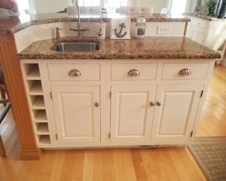 Kitchen island features wine storage and a bar sink