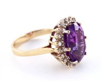 A vintage 14k Gold, Amethyst and Diamond cocktail ring. Features an oval cut prong set Amethyst approx. 10 x 14 mm, surrounded by twenty round cut prong set Diamond accents. Unmarked, tested 14k. 6.8 grams total. Minor surface wear. Size 9 3/4.