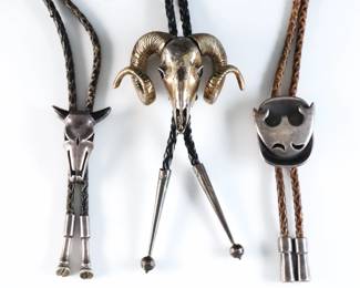 Three vintage Sterling Silver bolo ties. Includes a Southwest tie with Ram skull design, and two Mexican made ties with inlaid Deer skull and abstracted Eagle designs, on braided leather ties. Each marked or tested Sterling including aiguillettes. 6.59 troy ozs total. Some wear to surface and patina, two with wear to leather ties. Clasps up to 3" high, up to 21" long overall.