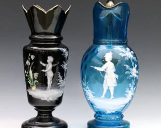 Two pieces of late 19th century Mary Gregory Art Glass. Enameled figural court decoration and Gilded detail, includes a Blue thumbprint glass pitcher with Amber glass handle, and a Black glass baluster vase with flared sawtooth rim. Minor surface wear, vase rim with tiny flakes. Up to 13 1/4" high.