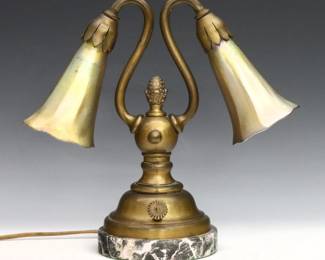 An early 20th century Bronze desk lamp with Tiffany Favrile glass shades. Double swan neck with floriform Gold Tiffany Favrile glass shades over a cast Bronze base with artichoke finial and Grey Saint Anne Marble foot. Shades signed "L.C.T." at fitters. Some wear to patina and slight pitting, small illegible signature incised at back, small flake to fitter. Shades are 4 1/4" high, lamp is 9 3/4" high overall.