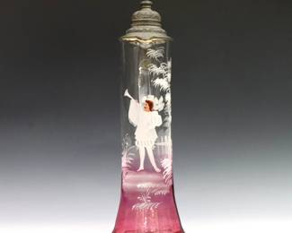 A late 19th century Mary Gregory Art Glass flagon. Tapered form in clear to Cranberry glass with flared foot, hinged pewter lid and enameled figural court decoration. Minor surface wear, lids sits askew. 18" high.