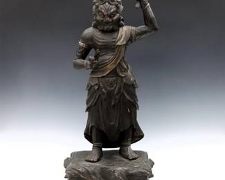A Japanese carved wooden temple figure of a Buddhist Deity. Depicted standing with one hand holding a Vajra and the other raised in Prana Mudra with painted finish on an incorporated base. Some wear, damage and repairs. 30" high.