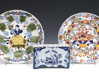Three pieces of 17th and 18th century Delft Earthenware. Includes two plates and a flower brick with polychrome scenic and floral decoration. Figural plate monogrammed "PK" by Jacobus Pynacker, flower basket plate "CL" attributed to Lambertus Cleffius and the flower brick unsigned. Crazing, flower brick repaired, plates with some edge flakes. Up to 9 1/4" diameter and 3 1/2" high.