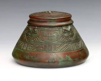 A turn of the century Tiffany "American Indian" pattern Bronze inkwell. Conical form with cast Native American style design, glass insert and patinated finish. Impressed "Tiffany Studios / New York / 1183" at underside, insert faintly marked "PATD Mar 1900". Minor wear and slight pitting, glass insert damaged. 3 1/2" high.
