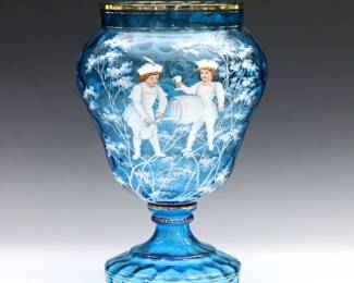 A late 19th century Mary Gregory Art Glass vase. Urn form in Blue thumbprint glass with pedestal base and enameled figural decoration with Gilded detail. Minor surface wear, flakes at rim and foot. 12" high.