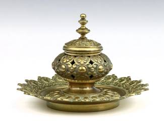 An early 20th century Bronze inkwell. Pierced floral design on a circular scalloped tray. Some oxidation, minor wear and pitting. 8" diameter x 5 1/4" high overall.