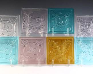 Eight turn of the century American pressed glass window panes attributed to the Mosaic Glass Company, Fostoria, OH. Various floral and swan designs in Aqua, Amethyst, Amber and clear. Some with minor flakes or small chips along edges. Each 4 x 4" high overall.