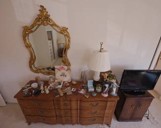 Bedroom furniture including a John Widdicomb French Provincial bedroom set, a side table cabinet and flat screen tv, vintage French style gilt framed wall mirror, lamp, vintage silver backed vanity set, collectible figurines (including a Goldscheider Everlast hallmarked Chinese fan dancer by Barbara Loveday, and a 1940s-1950's Hedwig "Hedi" Schoop tall Asian woman figurine.