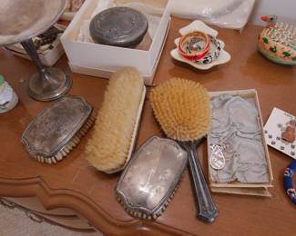 Closeup of vintage / antique silver backed vanity set of brushes; costume jewelry, porcelain animal form lidded boxes