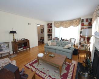 Another view showing books, sofa, brass andirons and fireplace screen, and a fabulous Baker Furniture mid century modern curved front tambour doors fruitwood server