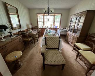 Dining room set with table and 6 chairs, china cabinet and hutch, side buffet. Other items in room are antique chair at the front center, table of glassware in the middle, and glassware along window ledge.