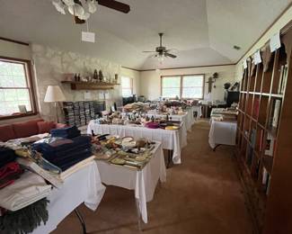 Living Room with 7 tables of miscellaneous goods; antique books; bookcases of books; a table with blankets, new sheets, towels, linens, etc; electric fireplaces; CDs, records, DVDs, sheet music; etc