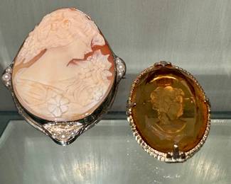 ($200; carved cameo pin with pearl accents) ($80; amber pin with carved cameo)