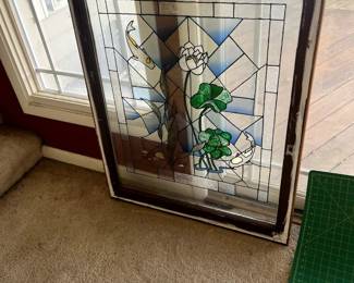 Handcrafted Stained Glass Panel – Floral Motif	Vibrant greens, purples, and yellows with symmetrical floral pattern in wood frame. Can be hung or inset into a window.
