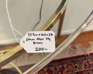 R27 - $200. Vintage Ethan Allen Brass Console Table with glass table. Measures 53.5" wide x 16" deep x 28" tall.