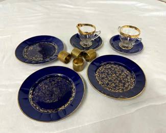 Blue and gold china plates, cups and saucers, and napkin rings