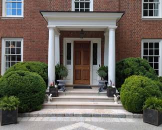 Inviting front entrance with pair of tall cast iron planters, w/fresh ferns, a pair of squatty cast iron planters with lavender trees, small pair of metal planters with freshly planted annuals, large pair of metal planters with happy ferns, pair of vintage cast iron swans and pair of horse head rings.