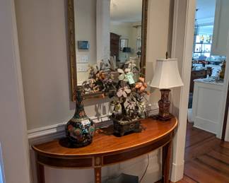 Beautiful banded mahogany demilune table, by Henkel-Harris, Asian stone flower arrangement, in cloisonne pot, Asian porcelain cachepot, small Asian table lamp, w/shade, finial, vintage Asian fan cachepot, antique French antique Louis XV style green and parcel-gilt wall mirror carved with a rocaille atop a vintage hand-woven Persian Hamadan rug, measures 3' 6" x 4' 10".