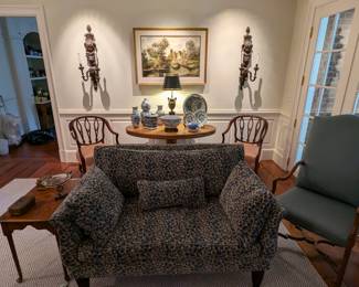 One of the pair of loveseats, covered in Brunschwig and Fils fabric, antique heart pine side table, pair of antique, Gorge III open armchairs, covered in silk fabric, heart pine oval dining table with collection of blue/white china, nicely framed/matted original oil on canvas art, pair of antique, hand-carved 2-light wooden wall sconces, w/lion motif and freshly upholstered vintage armchair , w/wooden stretcher.