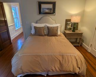 Nice queen size bed, with custom-made linens, upholstered headboard, 2-drawer "Grace" bedside table, w/open base, by Ballard Designs, contemporary table lamp and nicely framed artwork.