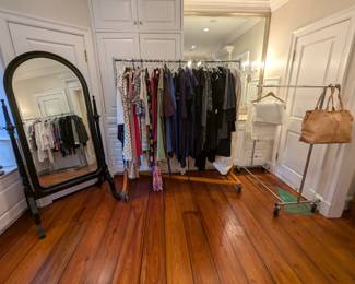Large floor mirror, with women's dresses and a few purses.