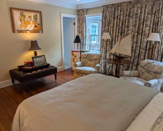 Pair of toile upholstered armchairs, antique pine tilt-top table with wooden model ship on wooden stand, brushed nickel quilt rack, with four vintage cotton quilts.