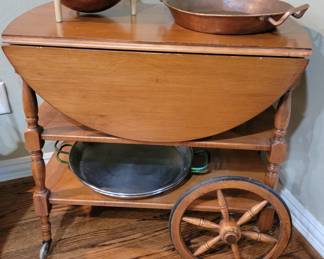 Serving cart displaying paella pans, copper baking and mixing bowls