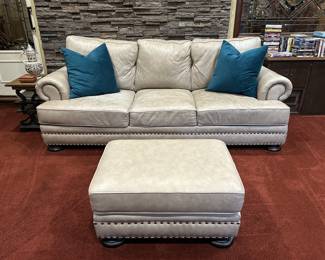 Leather sofa and ottoman with nailhead trim.