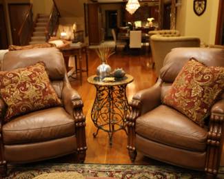 Two leather chairs with pillows and accent table with decor