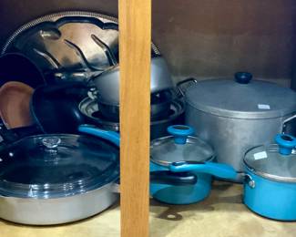 View of kitchen cabinets showing various aluminum pots and pans