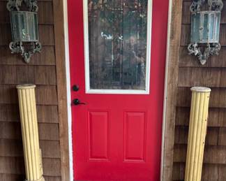Entry door showing a pair of antique metal wall mount candle lanterns and a pair of fluted great style Doric columns