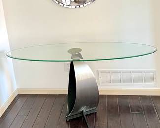 Modern console table featuring a beveled oval glass top with a sculptural metal base.
5 ft long, 18” deep, 29” Tall