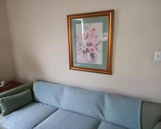 Delicate floral artwork in an elegant gold-toned frame. Features soft pink cherry blossoms against a light background. This tasteful piece would add a touch of serenity and refinement to any living space, bedroom, or hallway.Wall art