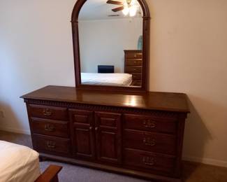 Wooden dresser with attached mirror and multiple drawers