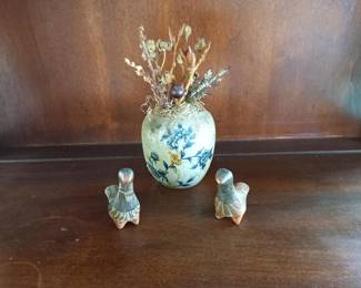 Decorative vase with flowers and small figurines on wooden table