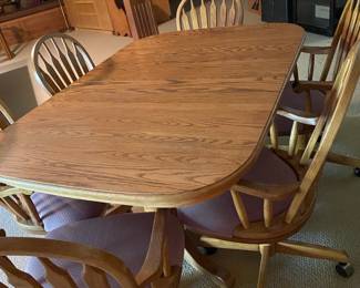 Nice oak kitchen/dining table with 6 chairs on rollers.