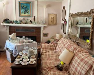 Tea cups with saucers, mirrors, couch (covered to keep it clean - it's teal blue), blown-glass fish (on mantle) and china sets