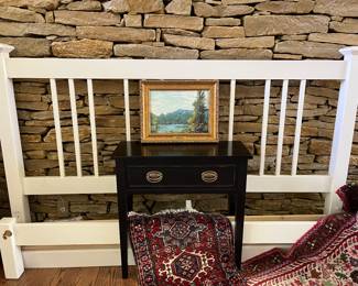 King size bed frame, little black table and Persian rugs.