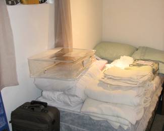 Luggage and 1 of 2 twin beds, linens
