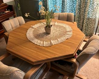 Dining room table with four chairs on wheels.