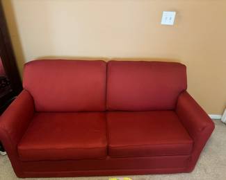 Comfortable red medium-sized couch. Can pull out into a bed.
