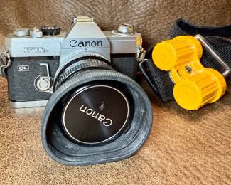 Canon FTb QL film camera with a 50mm f/1.8 lens and film canisters on neckstrap