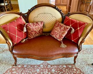 Victorian style settee with leather seat and accent pillow