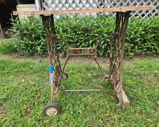 Vintage 'SINGER' sewing machine base frame on wheels with a wood work table.