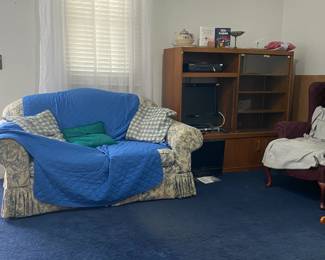 COUCH WITH PILLOWS, VHS PLAYER, DVD PALYER, TV, VINTAGE CHAIR, ITEMS ON TOP OF THE TV STAND.