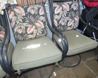 Two of four swivel patio chairs with cushions.