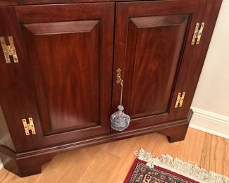 #18 - $1,000 - Henkel Harris corner cabinet mahogany 41x82x30D on the side wall. 18th century museum reproduction piece
