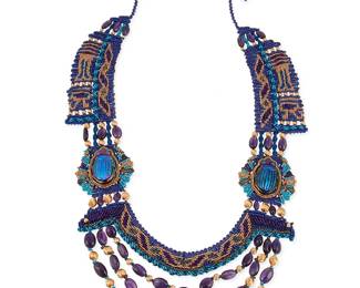 1094
Barbara Natoli Witt: A Macramé and Louis Comfort Tiffany Glass Scarab Necklace
Designed with elaborate dark blue, purple, and metallic gold cord Cavandoli macramé knotwork with ancient Egyptian motifs, featuring two Tiffany & Co. iridescent favrile glass scarabs re-set in 18k gold, suspending multiple swags of 14k gold and amethyst beads, circa 1991/1992, signed and dated to ceramic bead
42 in. x 3 in.
146.9 grams gross
Estimate: $1,000 - $2,000
